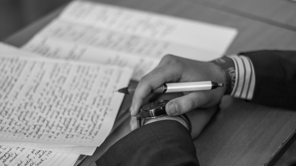 hands with pen at desk writing a soliloquy